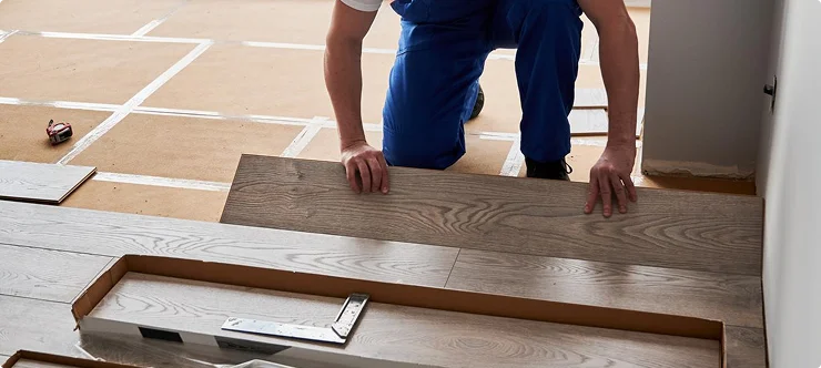 Contractor laying hardwood laminate flooring planks during installation