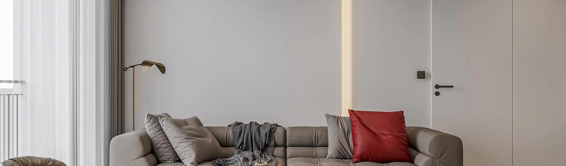 Contemporary living room with gray sectional sofa, red accent pillow, and vertical LED strip light